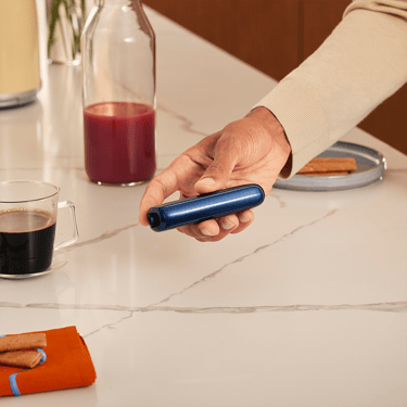 Mano sosteniendo un dispositivo Ploom AURA con el accesorio Panel Frontal Navy Blue