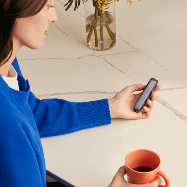 Mujer sosteniendo un dispositivo Ploom con el panel frontal Lavender