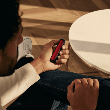 Hombre sosteniendo un dispositivo Ploom con el panel frontal Lava Red