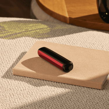 Accesorio Panel Frontal Lava Red para Ploom AURA puesto en el dispositivo, sobre una mesa.
