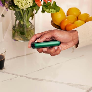 Mano sosteniendo un dispositivo Ploom con el panel frontal Amazon Green
