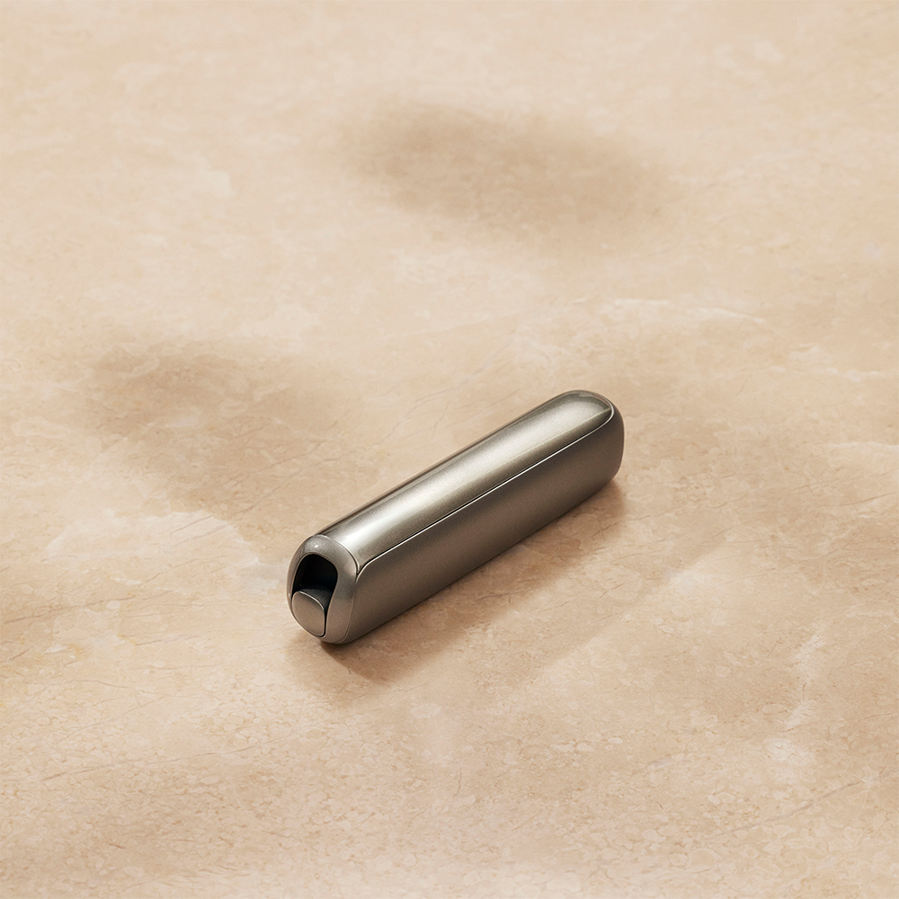 Primer plano de un accesorio Panel Frontal Lunar Silver para Ploom AURA sobre una superficie plana

